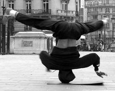 a man doing a handstand on his skateboard in front of a building