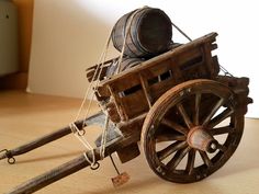 an old wooden cart with two wheels and rope on the front, sitting on a wood floor