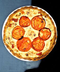 a pizza with tomatoes on it sitting on top of a table