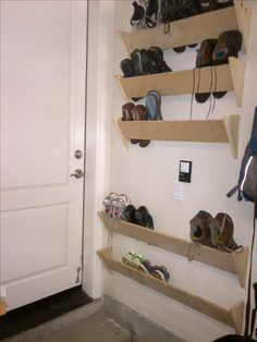 shoes are lined up on the wall in front of a door and some shelves above them