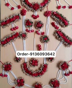 red flowers and pearls are arranged in rows on a table with white ribbon around them