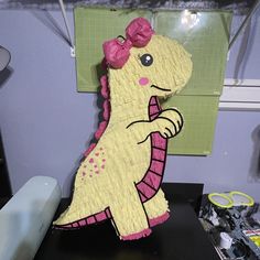 a paper mache of a dinosaur with a pink bow on it's head