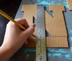 someone is cutting out the letters on cardboard with a tape and a pencil in front of them