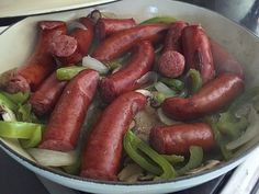 hot dogs and onions cooking in a pan on the stove