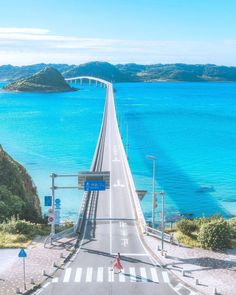 an aerial view of a long bridge over the ocean with blue water in the background