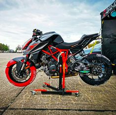 a motorcycle is parked in front of a vehicle with red rims on it's tires