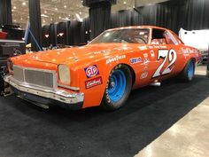 an orange race car on display in a showroom