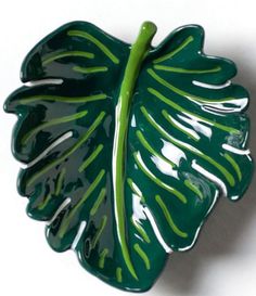 a green leaf shaped dish on a white surface