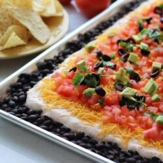 an appetizer with black beans, tomatoes and avocado is displayed on a tray