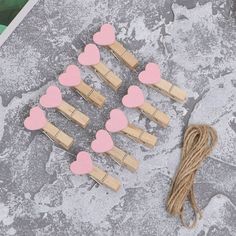 wooden clothes pins with pink hearts on them next to a string and some other items