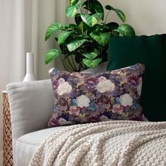 a white couch with a blanket on top of it next to a potted plant