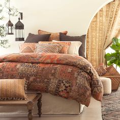 a bedroom with a large bed covered in orange and brown pillows next to a window