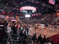 a group of people standing on top of a basketball court next to an arena filled with fans