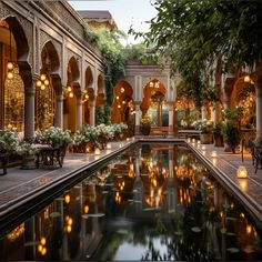 an indoor pool surrounded by potted plants and lights in the middle of a courtyard