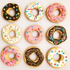 six donuts with different toppings are arranged in a row on a white surface