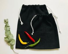 a black drawstring bag with two chili peppers on the front and one yellow pepper in the back