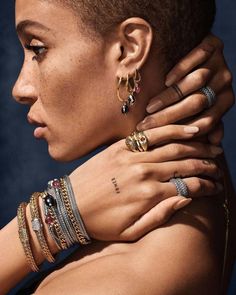 a close up of a person with rings on her neck and hands behind her back