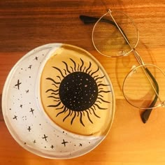 a plate with a sun and moon design on it next to some eyeglasses