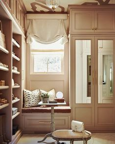 an empty walk - in closet with lots of shelves and drawers on the wall, along with a window seat