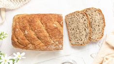 two loaves of bread sitting on top of a white table next to a glass of water