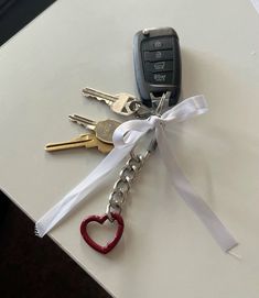 four keys tied together with a white ribbon and a heart shaped keychain attached to them