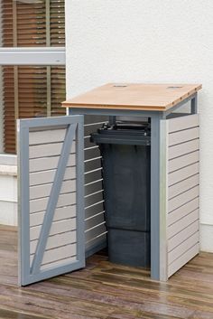 a trash can is in the middle of a wooden floor next to a building with shutters