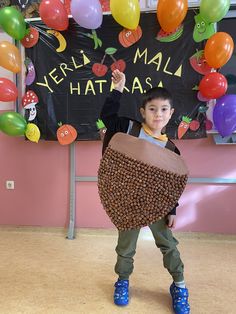 a young boy is holding up a basket with balloons on the wall in the background