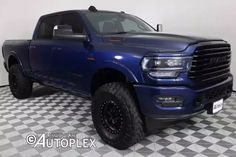 a large blue truck parked in a room with black and white checkered flooring