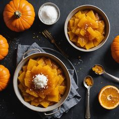 two bowls filled with food next to some oranges and spoons on a table