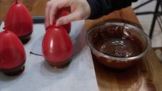 someone is decorating three red eggs with chocolate