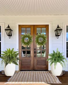 two wooden chairs sitting on top of a porch next to a couple of potted plants