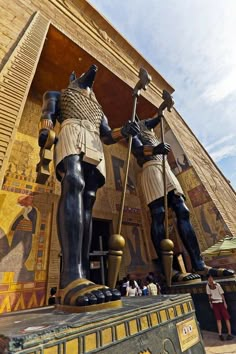 two statues of pharaohs standing next to each other in front of an egyptian building