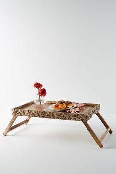 a tray with food on it sitting on top of a wooden table next to flowers