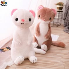 two stuffed animals sitting next to each other on a wooden floor