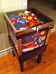 a glass table with an assortment of items in it on top of wood flooring