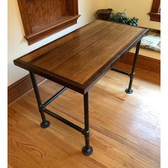 a wooden table sitting on top of a hard wood floor next to a wall mounted clock