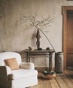 a white chair sitting next to a wooden table with a vase on top of it