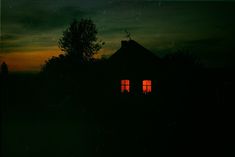 two windows are lit up at night in the dark sky, with trees behind them