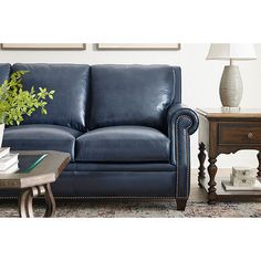 a living room with a blue leather couch and coffee table in front of the couch