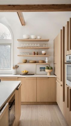 a kitchen with wooden cabinets and white counter tops next to an open window that looks out onto the woods