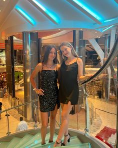 two young women posing for a photo in front of the stairs on a cruise ship