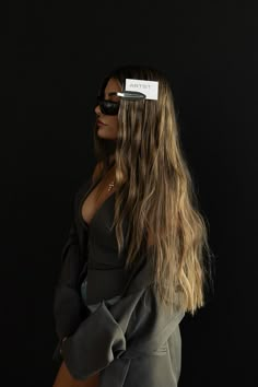 a woman with sunglasses on her head is standing in front of a black background wearing a gray suit