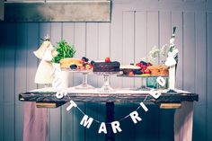 a table topped with cakes and desserts on top of a wooden table next to a wall