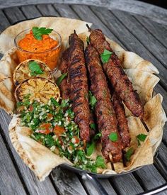 an assortment of meats and vegetables on a plate with a side of carrots