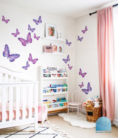 a baby's room with pink curtains and purple butterflies on the wall