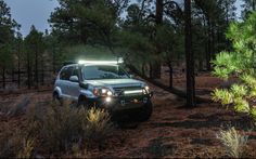 a car is parked in the woods with its lights on and headlamps on