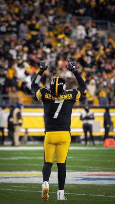 a football player with his hands up in the air while standing on top of a field