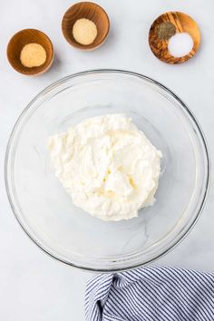 whipped cream in a glass bowl next to wooden spoons on a white counter top