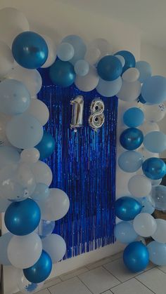 blue and white balloons are hanging from the wall