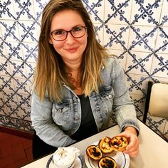 a woman sitting at a table with two pastries on the plate and coffee in front of her